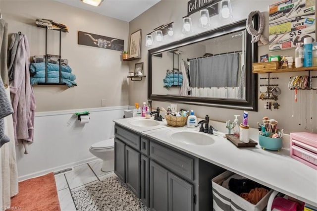 bathroom featuring toilet, double vanity, a sink, and visible vents