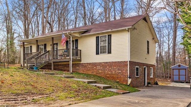 ranch-style house with driveway, an outbuilding, covered porch, a shed, and brick siding