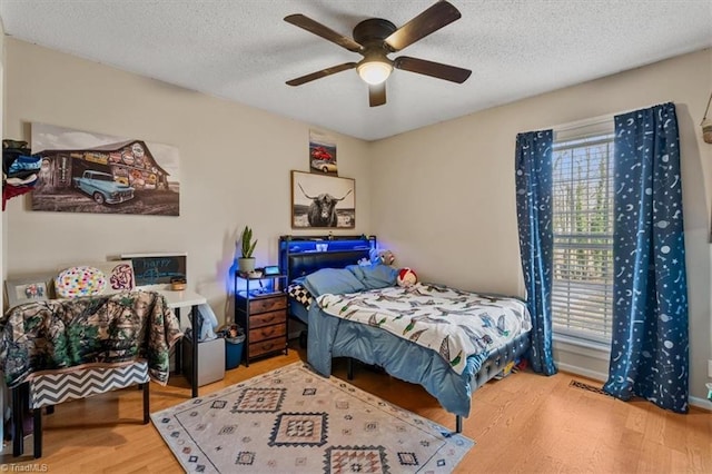 bedroom featuring a textured ceiling, a ceiling fan, and wood finished floors