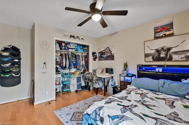 bedroom with a closet, a ceiling fan, a textured ceiling, wood finished floors, and baseboards