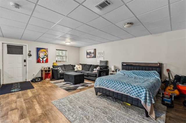 bedroom with visible vents, a drop ceiling, and wood finished floors