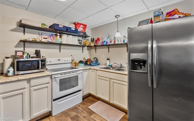 kitchen featuring open shelves, light countertops, appliances with stainless steel finishes, a sink, and wood finished floors