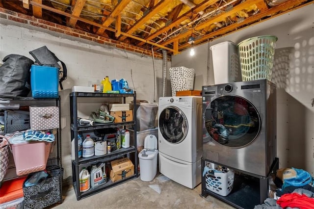 laundry room featuring concrete block wall, laundry area, and washing machine and clothes dryer