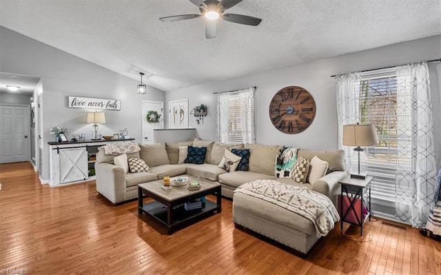 living room with vaulted ceiling, a textured ceiling, wood-type flooring, and a ceiling fan