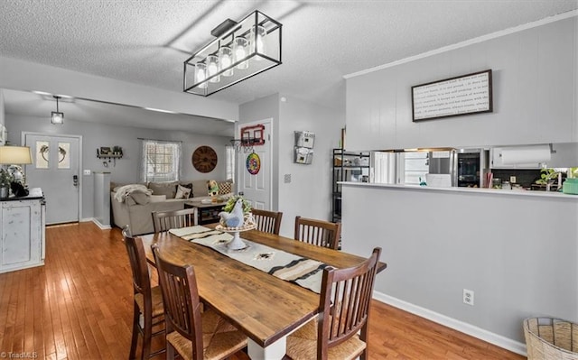 dining space featuring wood-type flooring, a textured ceiling, and baseboards