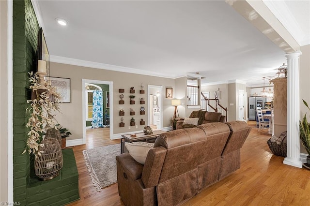 living room with ornate columns, crown molding, and wood-type flooring