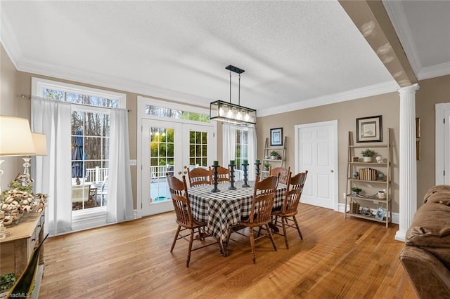 dining area featuring french doors, light wood-type flooring, a wealth of natural light, and crown molding