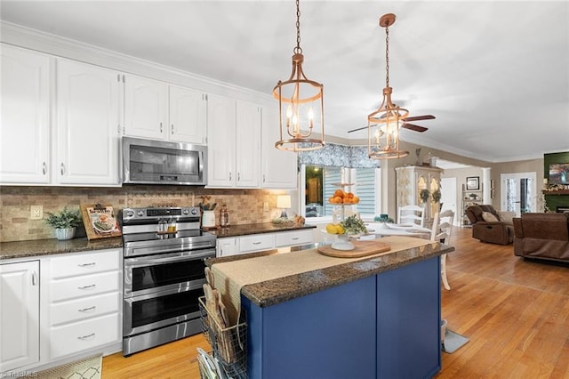 kitchen featuring backsplash, hanging light fixtures, white cabinets, and stainless steel appliances