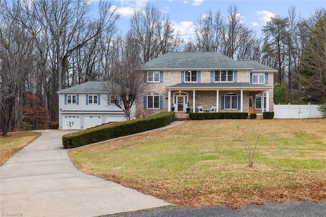 colonial home featuring a porch, a garage, and a front lawn