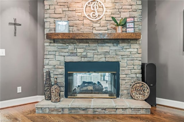 details with hardwood / wood-style flooring and a stone fireplace