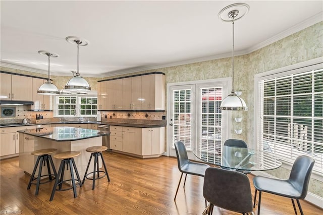 kitchen with crown molding, a kitchen island, hanging light fixtures, and light hardwood / wood-style floors