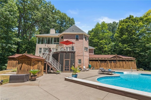 rear view of property featuring a fenced in pool, a sunroom, and a patio