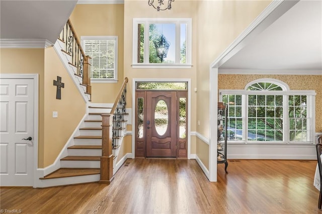 foyer featuring hardwood / wood-style flooring, a notable chandelier, and crown molding