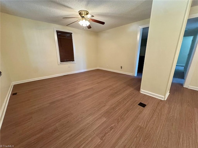 spare room with a ceiling fan, baseboards, a textured ceiling, and dark wood-style flooring