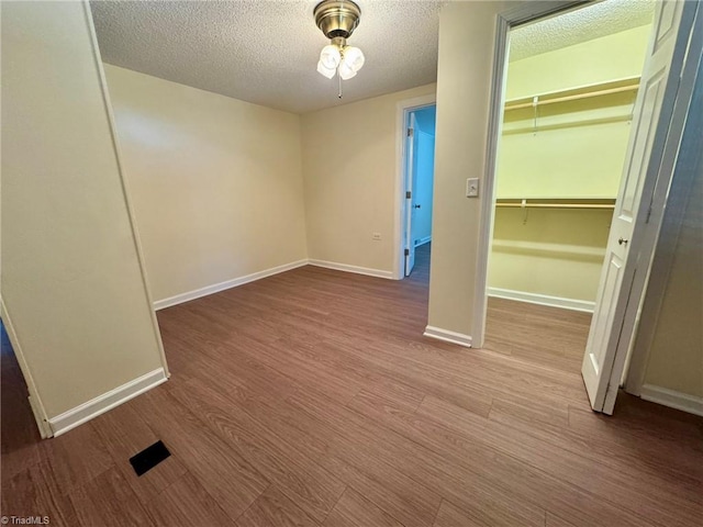unfurnished bedroom with wood finished floors, a textured ceiling, and baseboards