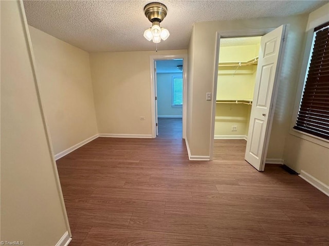 unfurnished bedroom with baseboards, wood finished floors, a textured ceiling, and a closet