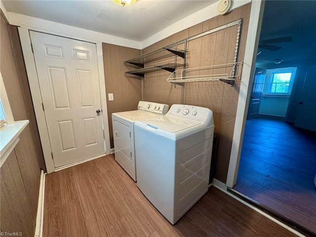 laundry area with wooden walls, light wood-type flooring, washer and clothes dryer, and laundry area