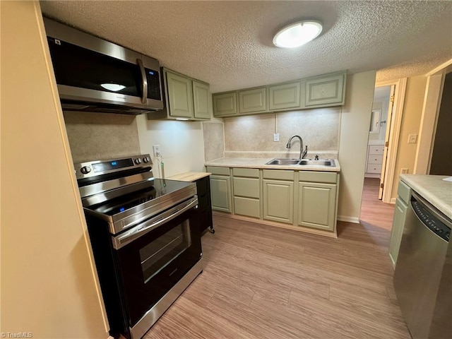 kitchen featuring a sink, a textured ceiling, decorative backsplash, light countertops, and appliances with stainless steel finishes