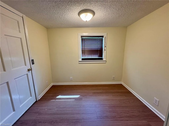 spare room with baseboards, wood finished floors, and a textured ceiling
