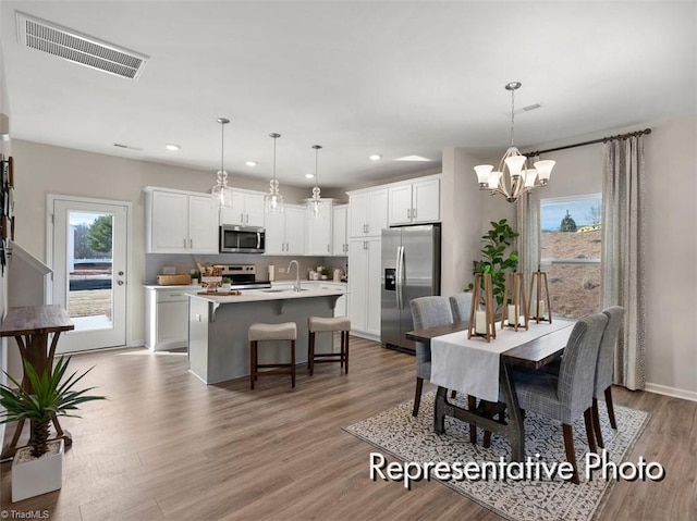 dining area with a notable chandelier, visible vents, recessed lighting, and wood finished floors