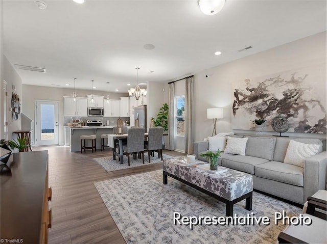 living room with a notable chandelier, plenty of natural light, dark wood-type flooring, and visible vents