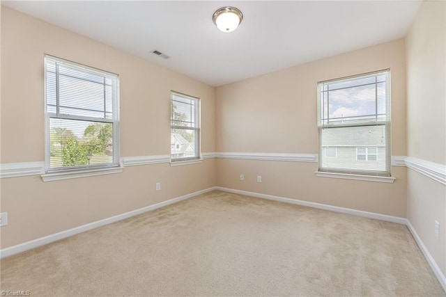 empty room featuring light carpet, visible vents, and plenty of natural light
