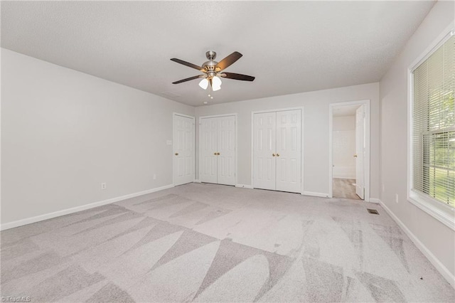 5207 Highland Oak Ct, Greensboro, NC 27410 - unfurnished bedroom featuring multiple closets, light colored carpet, ensuite bath, and a ceiling fan
