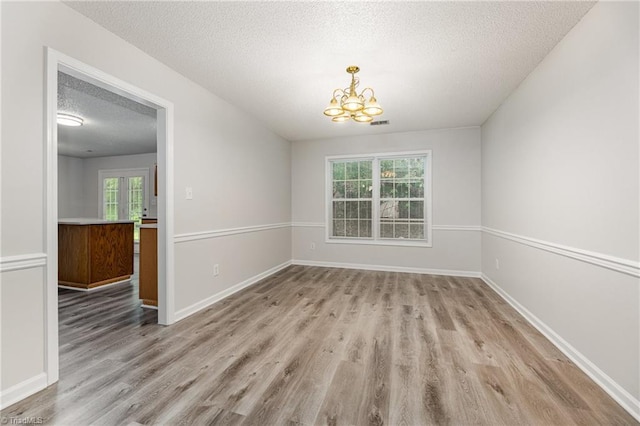 5207 Highland Oak Ct, Greensboro, NC 27410 - unfurnished dining area featuring a textured ceiling, a chandelier, and wood finished floors