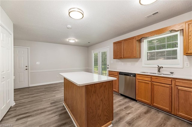 5207 Highland Oak Ct, Greensboro, NC 27410 - kitchen featuring stainless steel dishwasher, a kitchen island, light wood-style floors, light countertops, and a textured ceiling