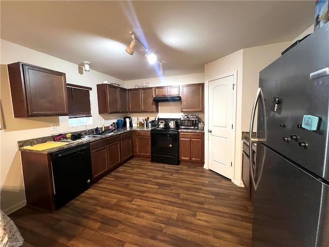 kitchen with dark brown cabinetry, appliances with stainless steel finishes, dark stone countertops, and dark hardwood / wood-style flooring