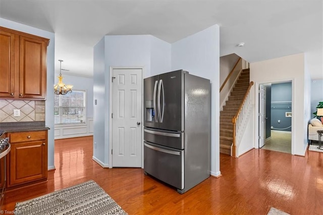 kitchen featuring brown cabinets, dark wood-style floors, dark countertops, and stainless steel refrigerator with ice dispenser