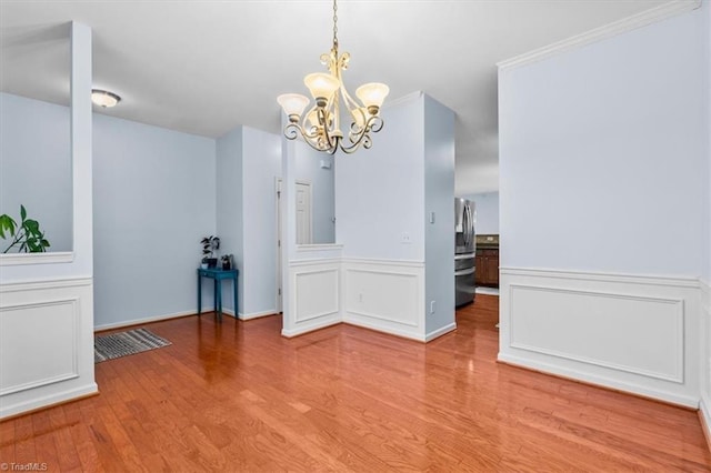 unfurnished dining area with a decorative wall, an inviting chandelier, and wood finished floors