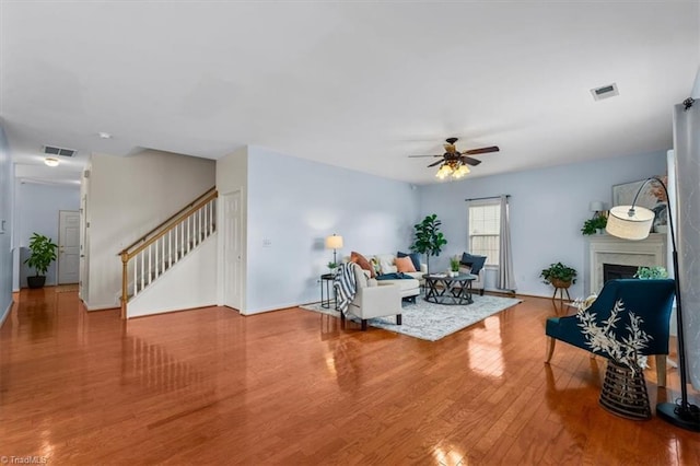 living area with stairway, a fireplace, wood finished floors, and visible vents