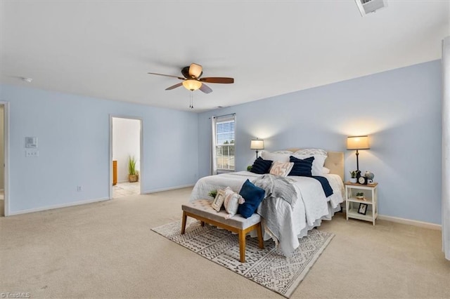 bedroom with light carpet, visible vents, baseboards, ensuite bath, and ceiling fan