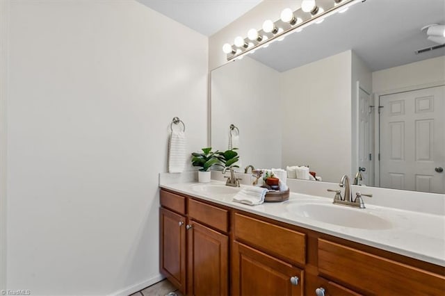 bathroom with visible vents, a sink, baseboards, and double vanity