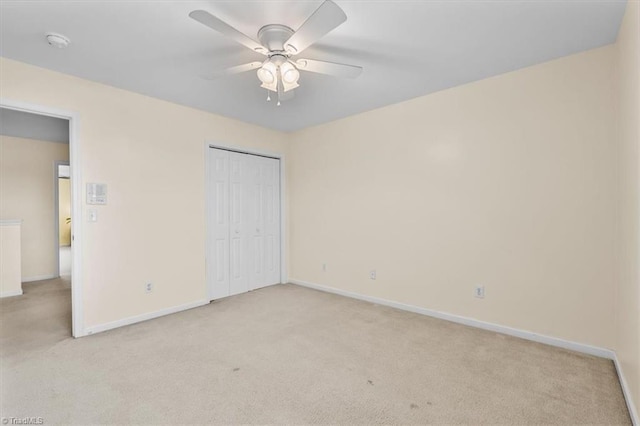 unfurnished bedroom with a ceiling fan, a closet, light colored carpet, and baseboards