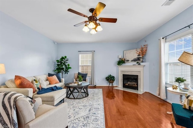 living room featuring plenty of natural light, a premium fireplace, visible vents, and wood finished floors