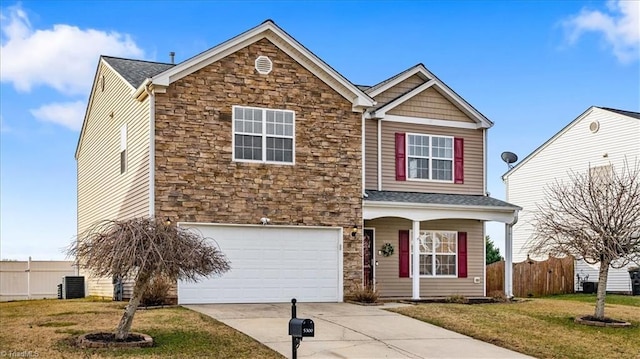 view of front of home with an attached garage, fence, stone siding, concrete driveway, and a front lawn