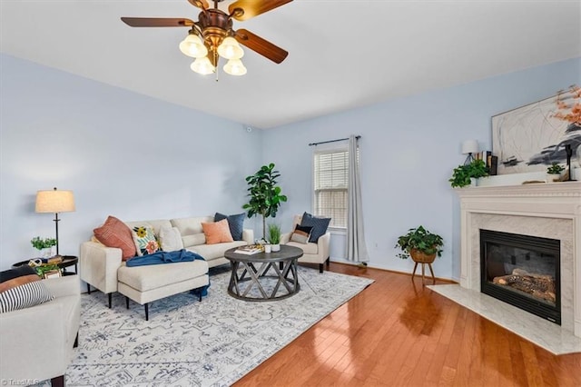 living area with ceiling fan, a premium fireplace, and hardwood / wood-style floors