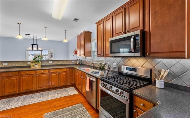 kitchen with dark countertops, visible vents, stainless steel appliances, and backsplash