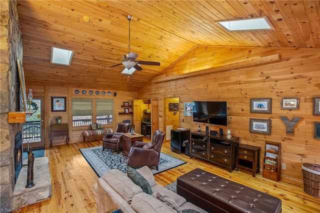 living room featuring a skylight, wooden ceiling, wooden walls, ceiling fan, and light hardwood / wood-style floors