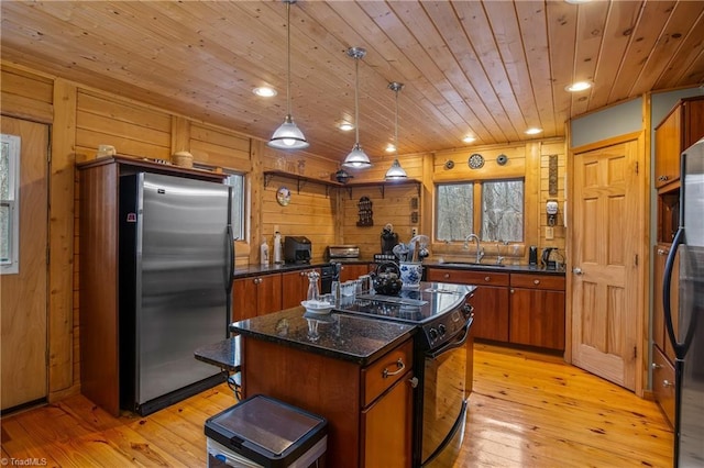 kitchen with sink, decorative light fixtures, a center island, black / electric stove, and stainless steel fridge