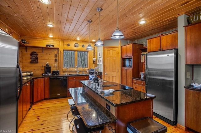 kitchen featuring decorative light fixtures, sink, a center island, black appliances, and light wood-type flooring