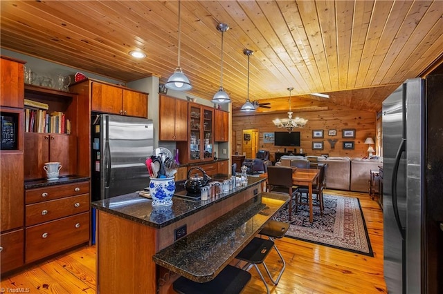 kitchen featuring stainless steel refrigerator, a center island, a breakfast bar area, and pendant lighting