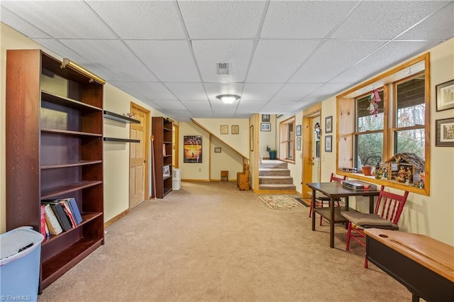 interior space featuring a paneled ceiling and light colored carpet