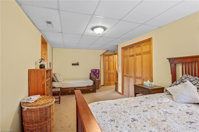 carpeted bedroom with a drop ceiling and a closet