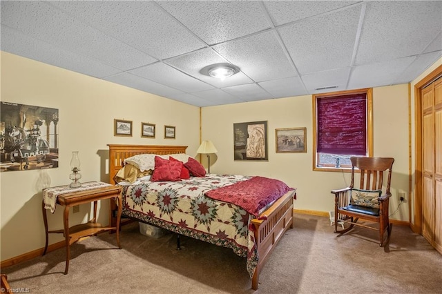 carpeted bedroom featuring a drop ceiling