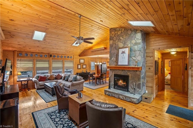 living room with light hardwood / wood-style flooring, a skylight, wooden walls, a stone fireplace, and wooden ceiling