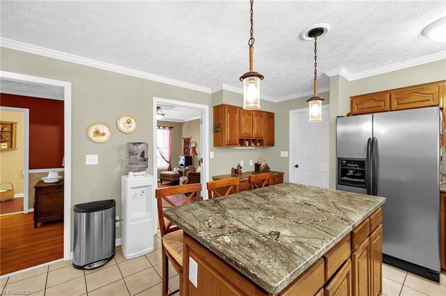 4717 Deaton Rd, Trinity, NC 27370 - kitchen featuring stainless steel fridge, a center island, light tile patterned floors, brown cabinets, and decorative light fixtures