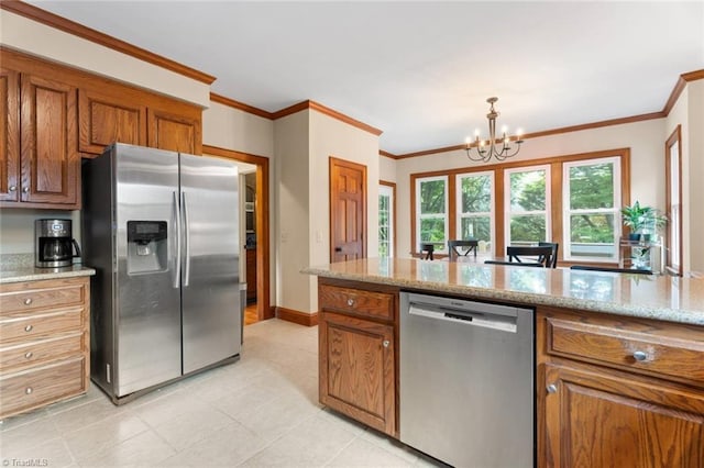 kitchen with stainless steel appliances, brown cabinetry, a chandelier, light stone counters, and crown molding